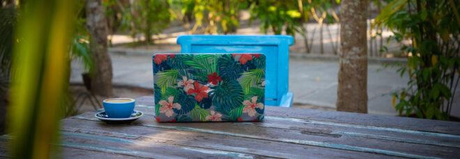 laptop with floral case on an outdoor table surrounded by trees