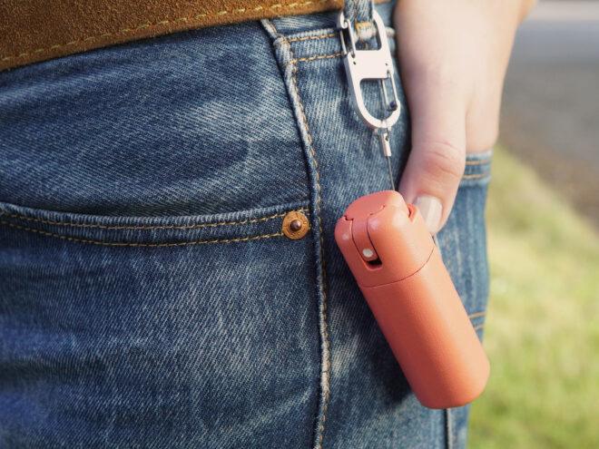 an orange bottle of sanitizer attached to the belt loop on a pair of jeans