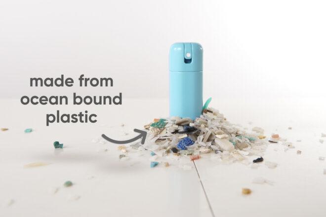 a blue bottle of sanitizer surrounded by a pile of plastic shards, with text pointing to it that reads "made from ocean bound plastic"