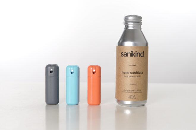 from left to right: a(n) gray bottle of sanitizer, blue bottle of sanitizer, orange bottle of sanitizer and tall silver bottle of sanitzer refills.
