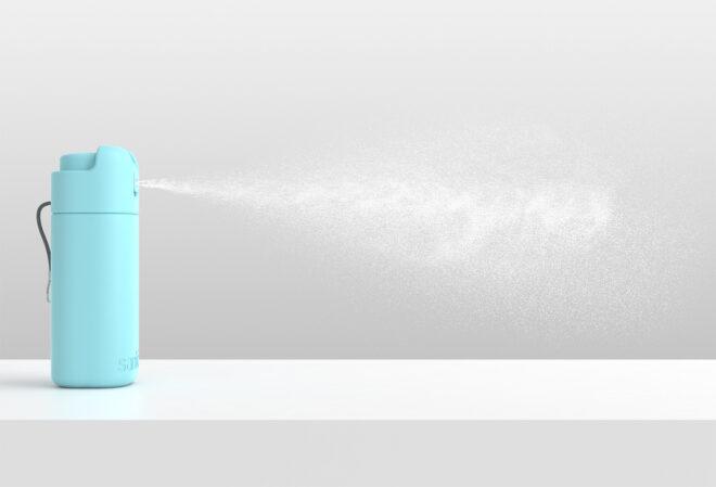a light blue bottle of hand sanitizer emitting a puff of spray against a white/gray backdrop