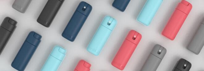 a repeating pattern flat lay of light gray, dark gray, dark blue, light blue and pink bottles of sanitizer