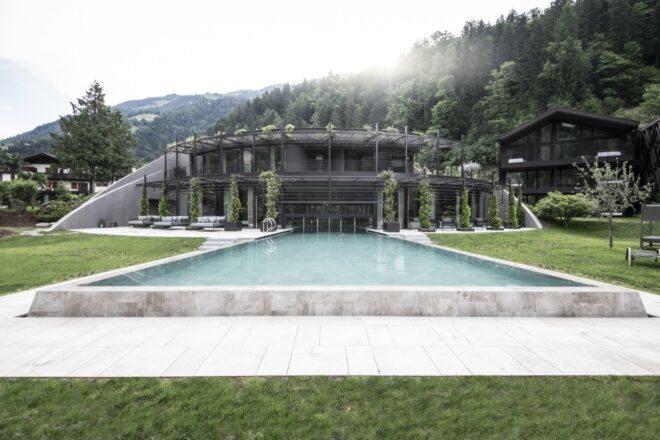 long pool leading to large black building covered in draping plants