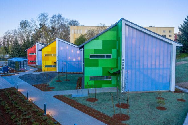 green, red and blue buildings with angled roofs and polycarbonate exteriors