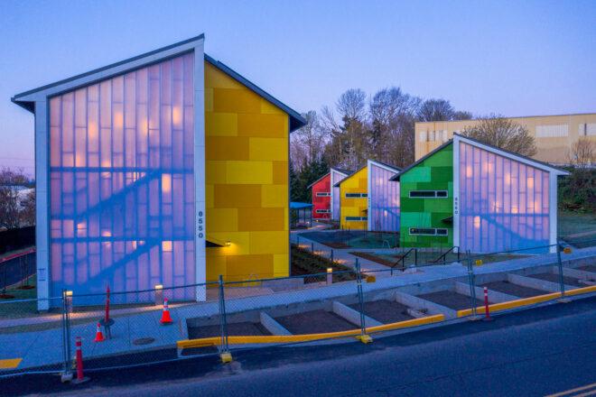 colorful, gabled buildings with partial polycarbonate exteriors lit from within at night