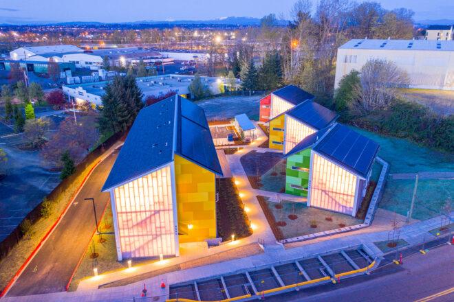aerial view of colorful gabled buildings with solar panels and light from inside shining through polycarbonate exterior