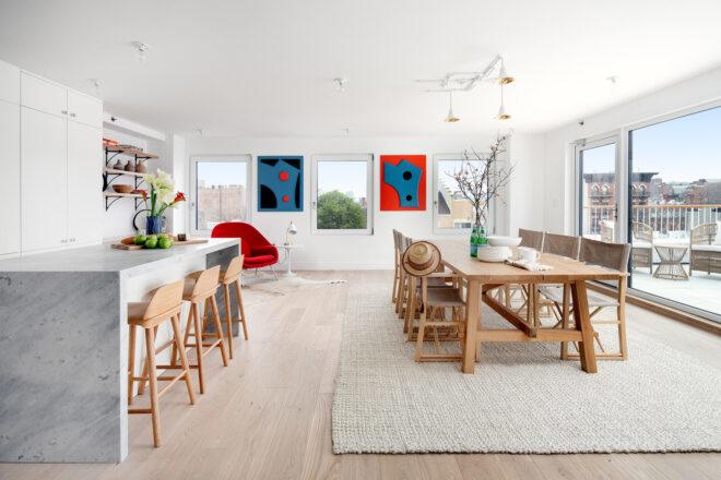 open-plan apartment with long wood dining table and marbled kitchen island