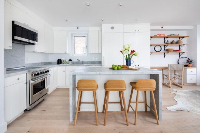 white kitchen with steel appliances and marble island