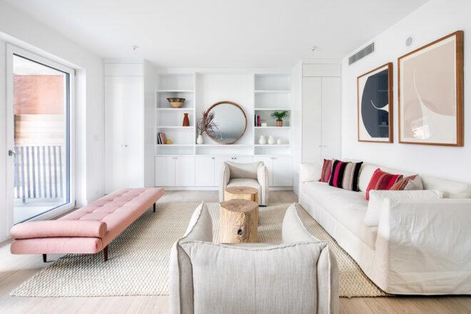 living room with pink chaise, white sofa and white built-in shelving