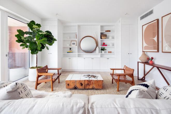 brown chairs and white couch in white room with built-in shelves