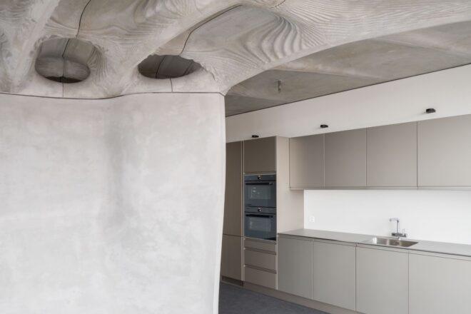 gray kitchen cabinets in concrete room with wavy ceiling