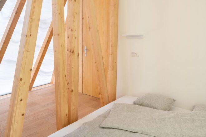 gray bed beside wood beams