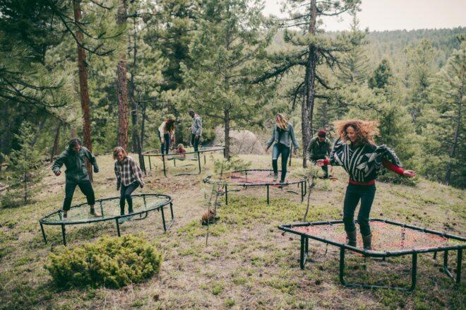 people jumping on artistic trampolines in a forest