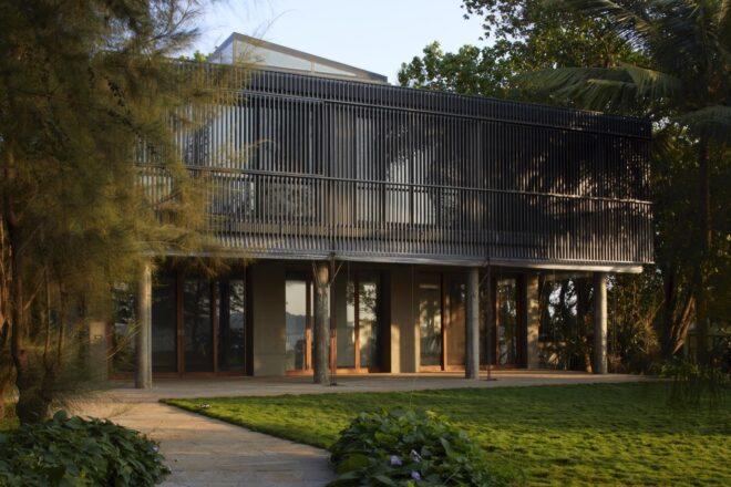 black home with slatted screens over the top-floor windows