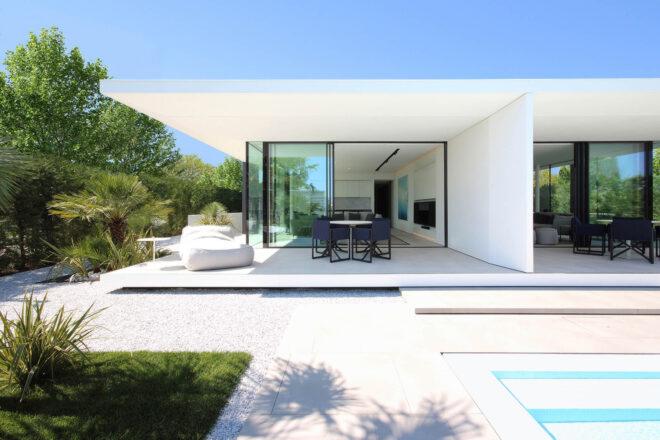 small yard and long pool outside white and glass beach villa