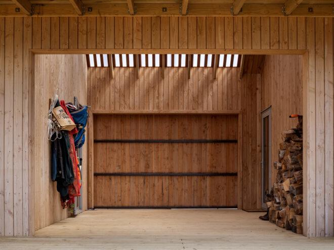 wood-lined room with hooks for coats and a stack of firewood