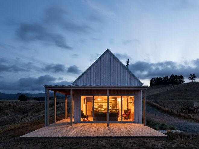 gabled wood farmhouse with porch lit up at night