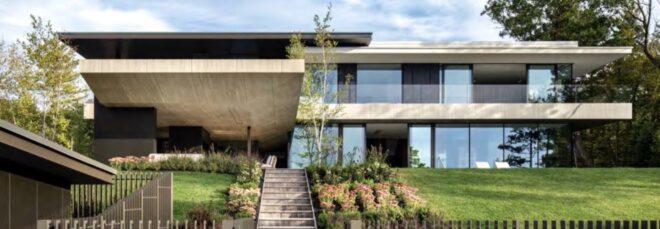 stairs leading up to cantilevered concrete home with large yard