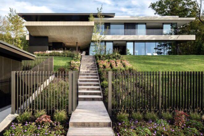 stairs leading up to cantilevered concrete home with large yard