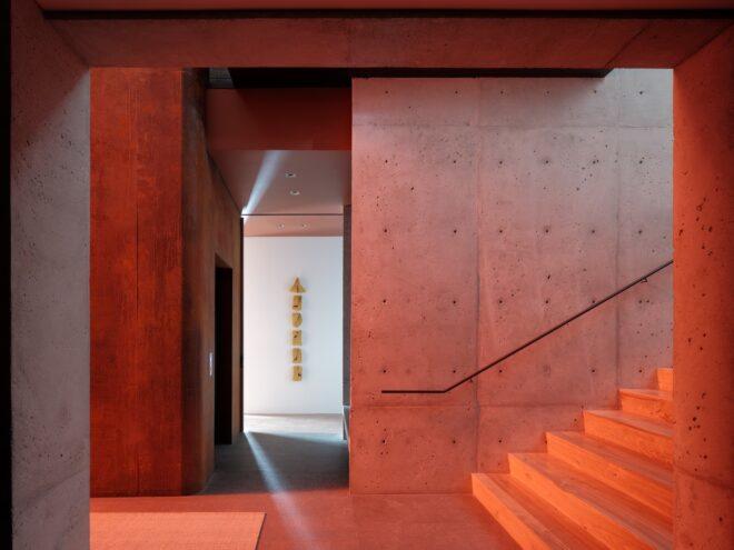 a staircase and hallway area with concrete walls lit up red.