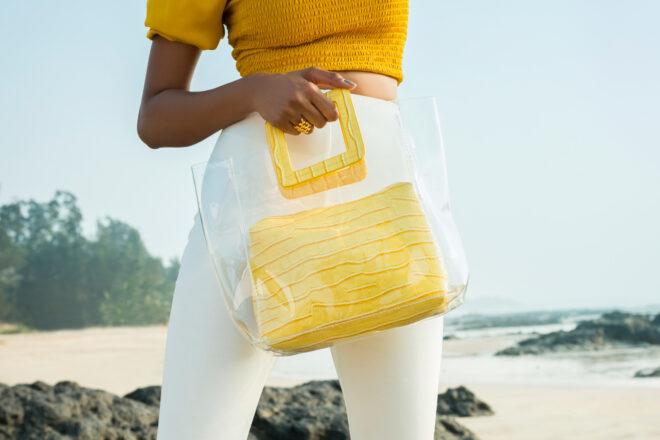 person with yellow top and white pants carrying a clear and yellow tote purse