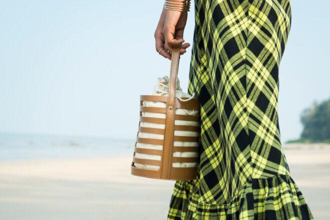 person carrying brown vegan leather bucket purse