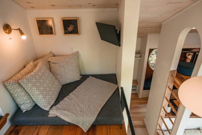 large gray bed and small wall-mounted TV on a loft