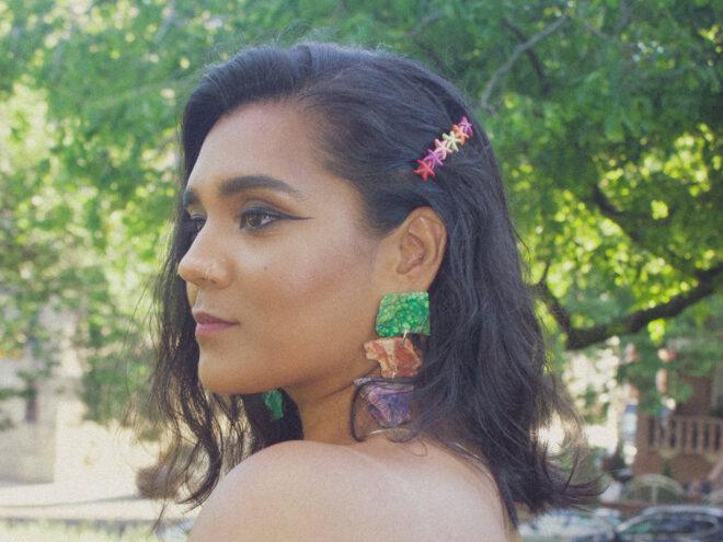 person wearing colorful stone earrings and colorful starfish hairclip