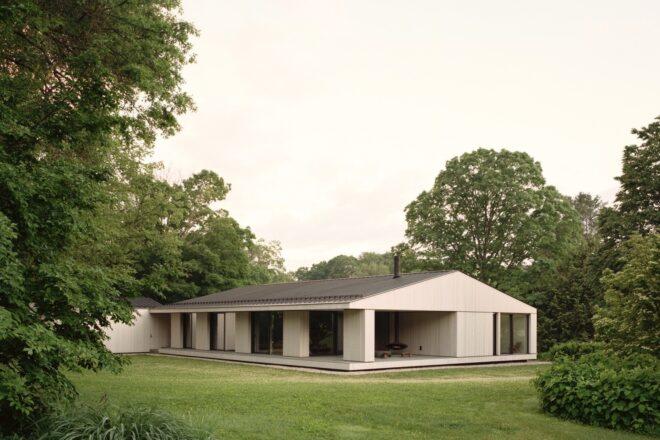 long gabled home clad in light wood panels