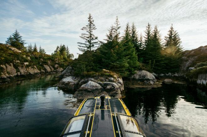 yellow boat with solar panels facing an evergreen forest