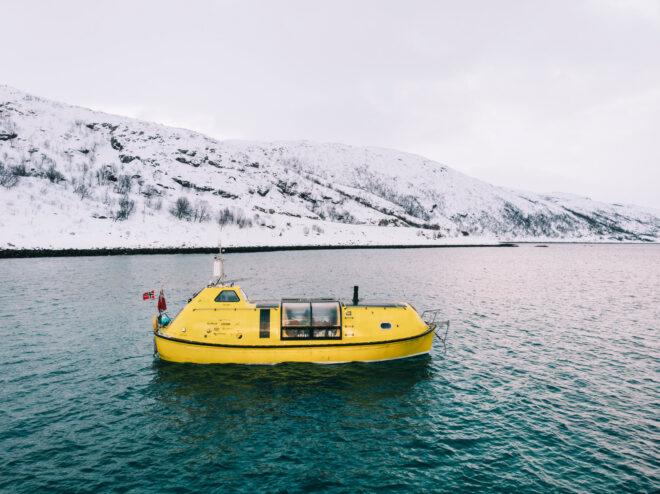 yellow boat on lake near snow-covered mountains
