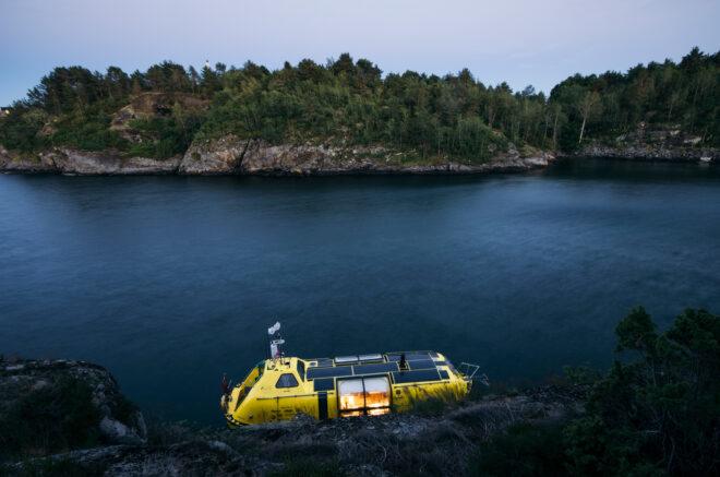 yellow boat docked across from island of evergreen forest