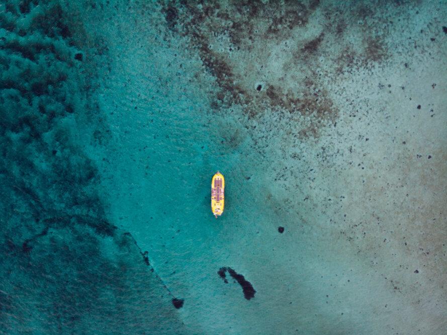 aerial view of solar-powered yellow boat on bright blue water
