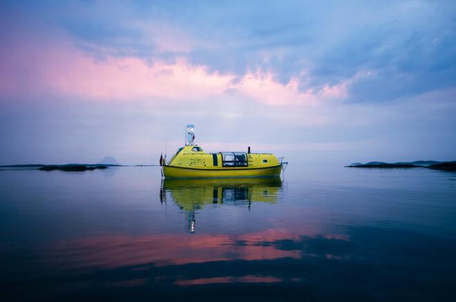 yellow boat on water against a pink and blue sunset