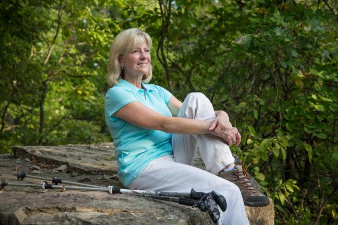 Susan Trautman, CEO of St. Louis’ Great Rivers Greenway, sitting on a rock in a park