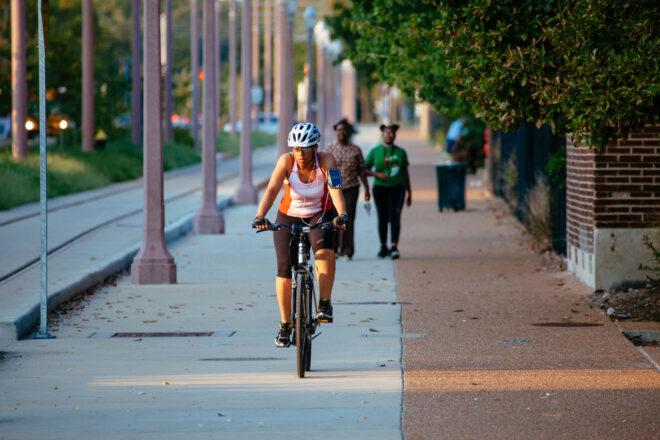 person riding bike on trail in city