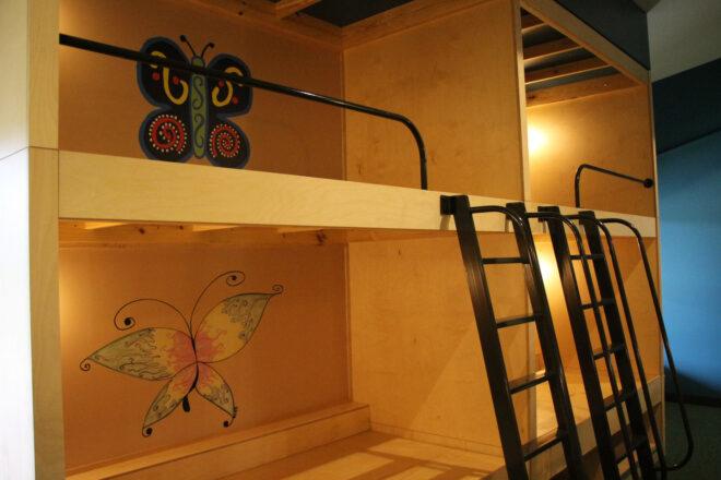 wood bunk beds with butterfly paintings on the wall