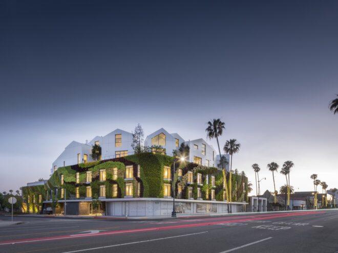 large green wall wrapping a white building with multiple gabled roofs at dusk