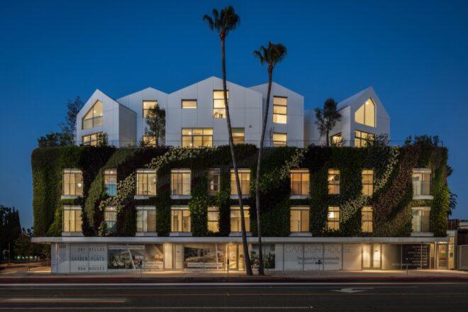 large green wall wrapping a white building with multiple gabled roofs at night