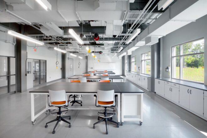 learning lab with large black tables and white and orange chairs
