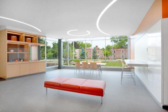lobby with red bench, white tables and chairs and a wall of glass