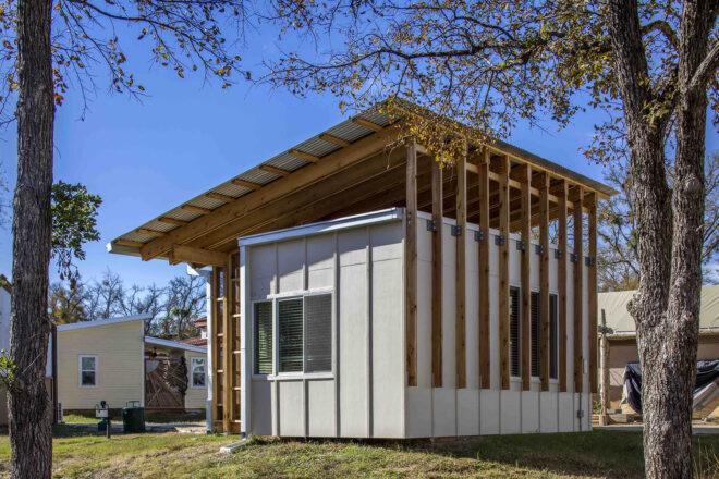 a micro-house with a roof slanted down to the left. the home's facade is white with wood accents.