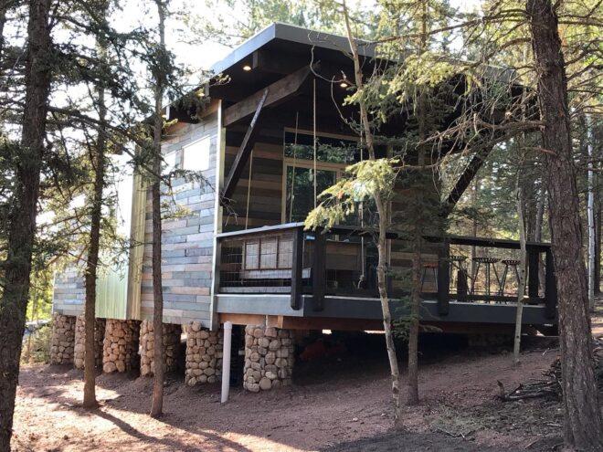 elevated dark wood cabin surrounded by trees