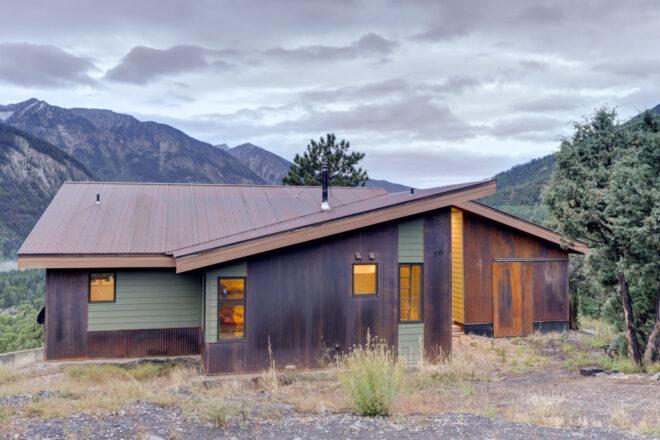 dark wood and weathered steel cabin in mountainous landscape