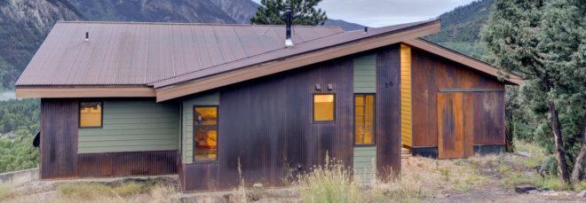 dark wood and weathered steel cabin in mountainous landscape