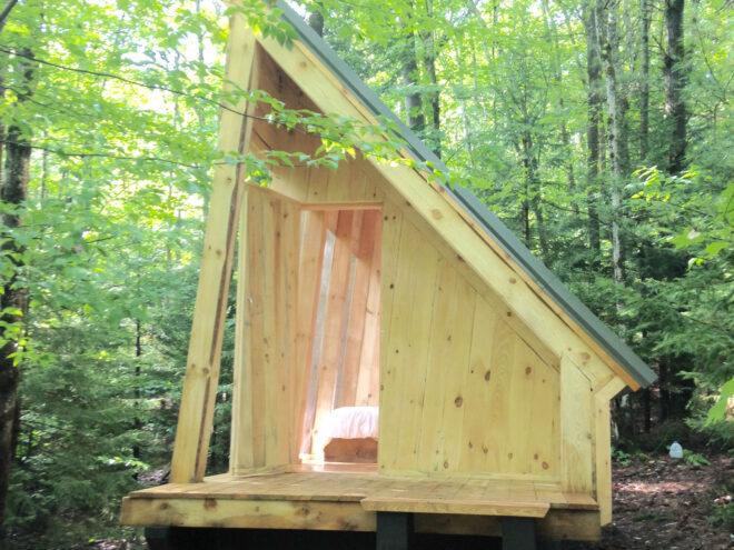 light wood cabin with sloped roof in a forest