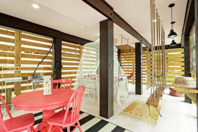 covered outdoor patio with red dining set and wood swings