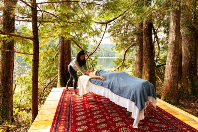 person giving another person a professional massage on a wooden deck in a forest