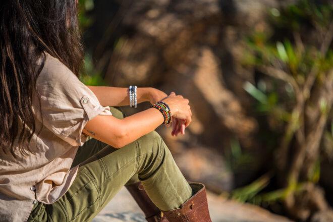 person sitting outside and wearing colorful beaded bracelets on both wrists