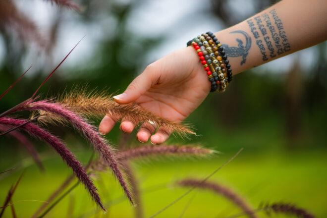 person with several bracelets on arm grabbing at a plant